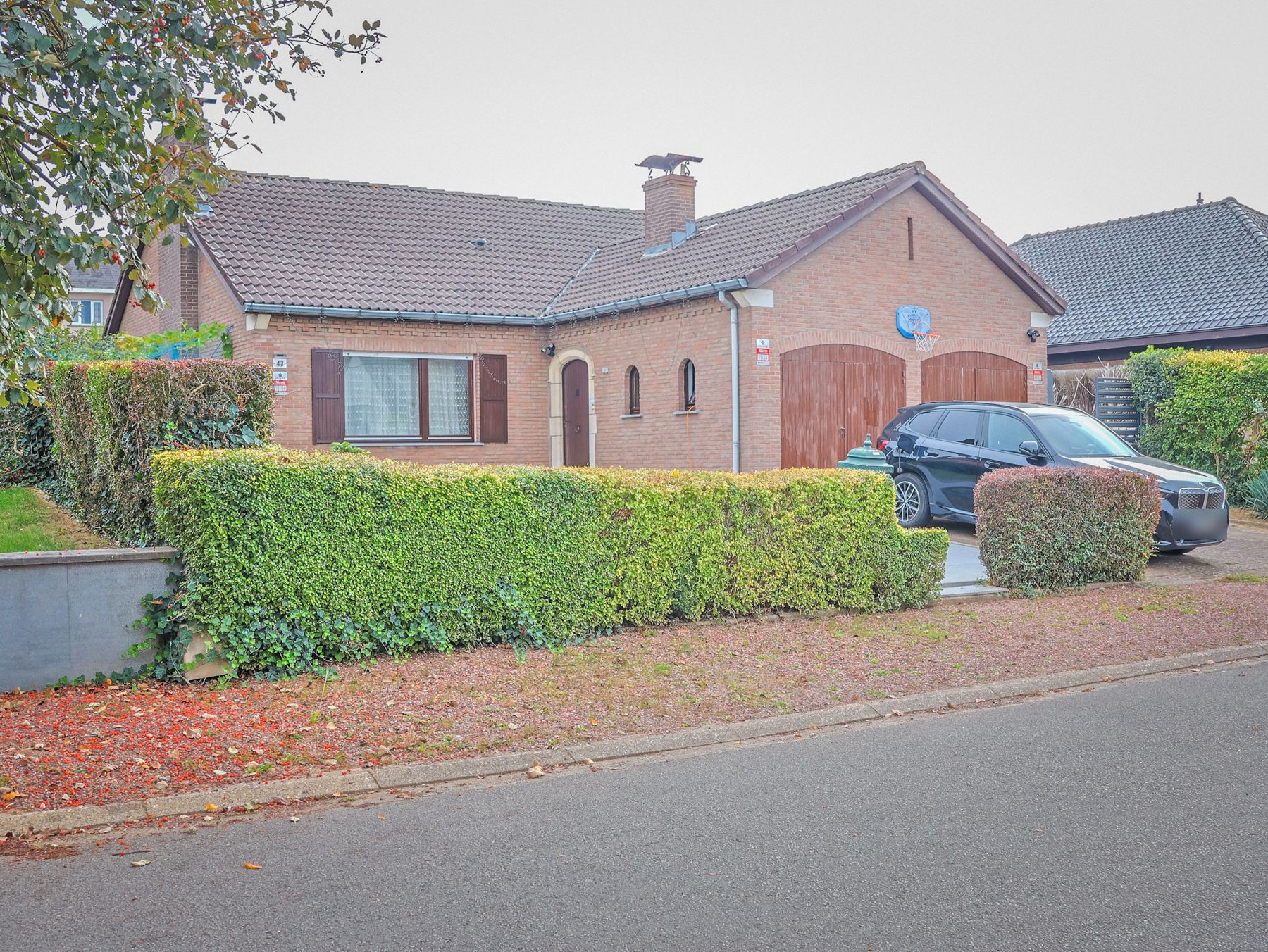 Front of the brick bungalow villa with its hedge and double garage