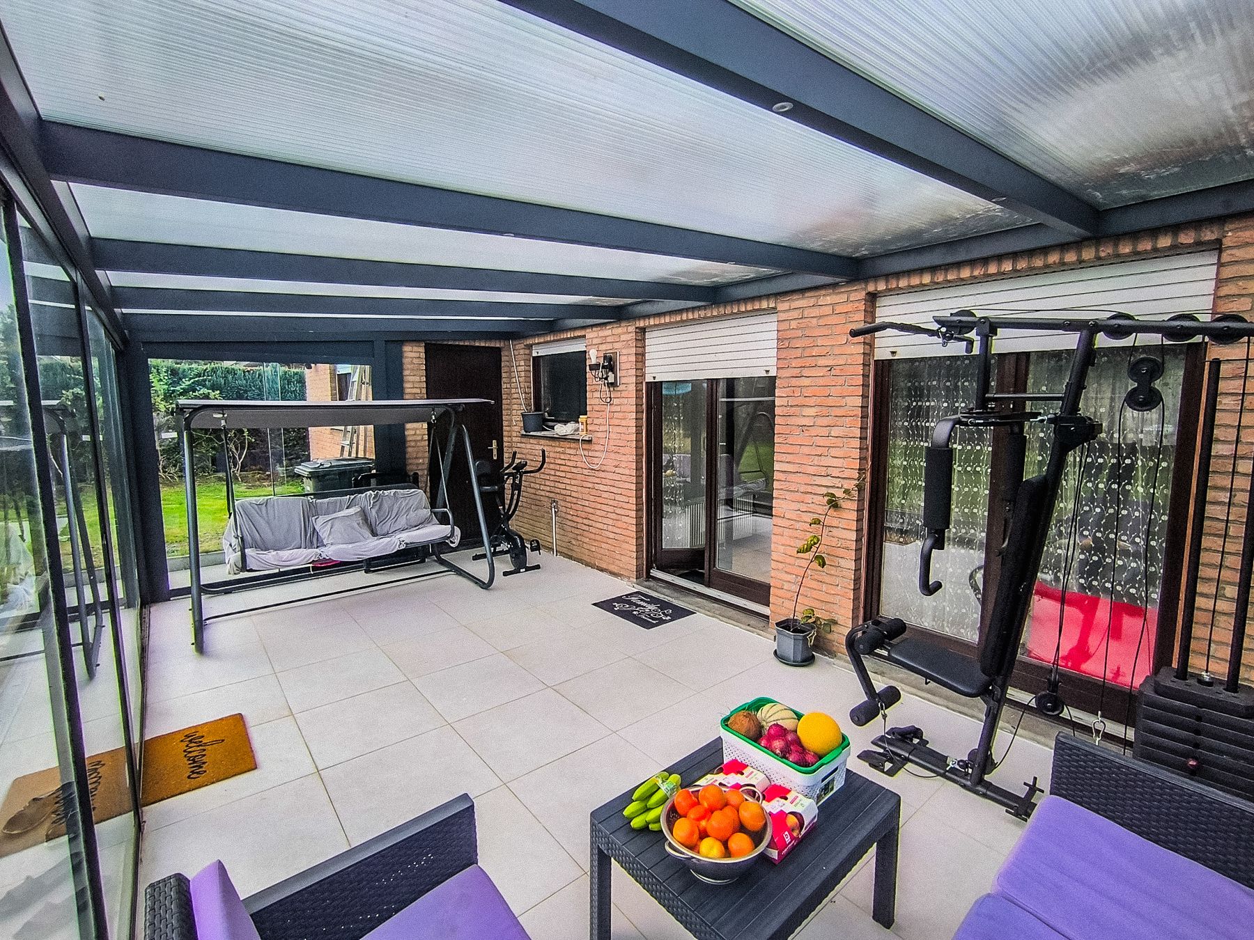 The veranda with its glass roof and sliding doors, looking out to the garden